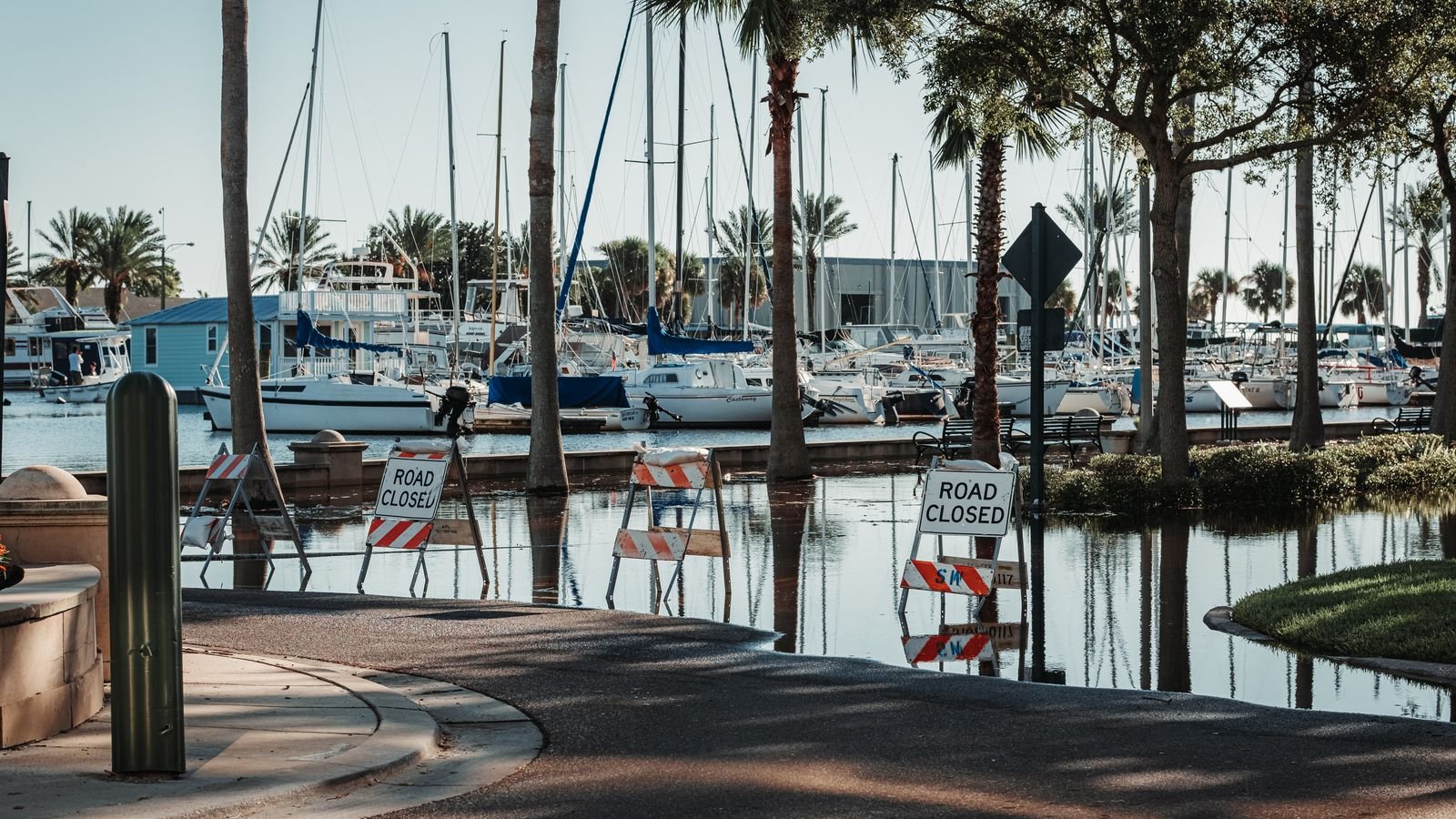 Flood water across a harbourside road, with road closed signs